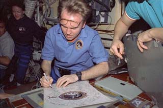 Mission Specialist Andrew Thomas signs chart that contains the names of all the astronauts and cosmonauts who stayed on Mir.